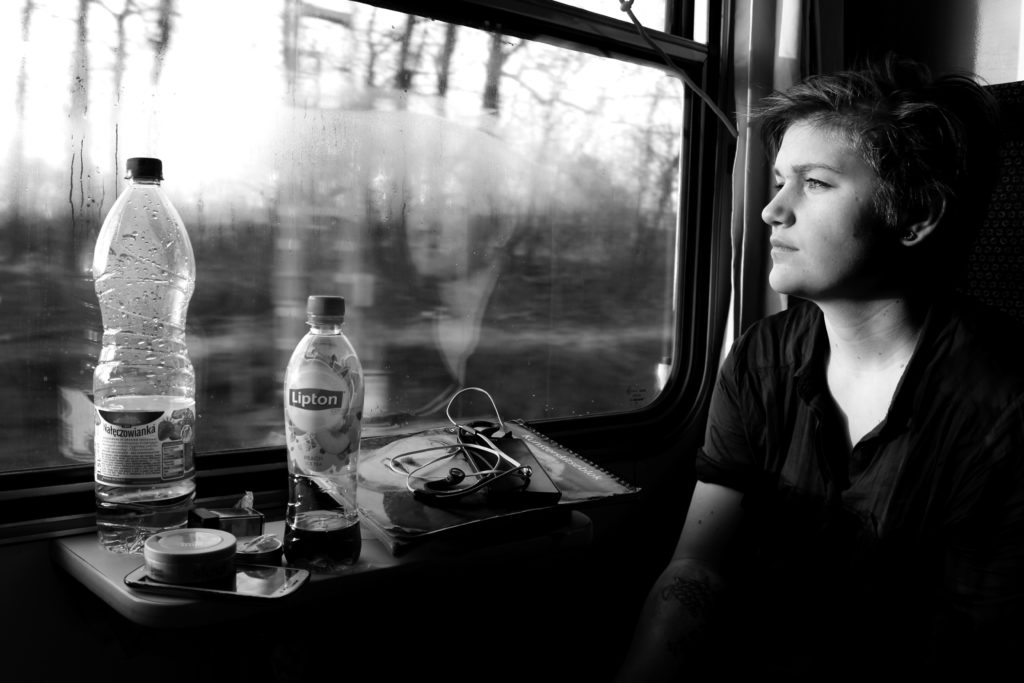 Ung kvinne ser ut av vinduet på tog på interrail