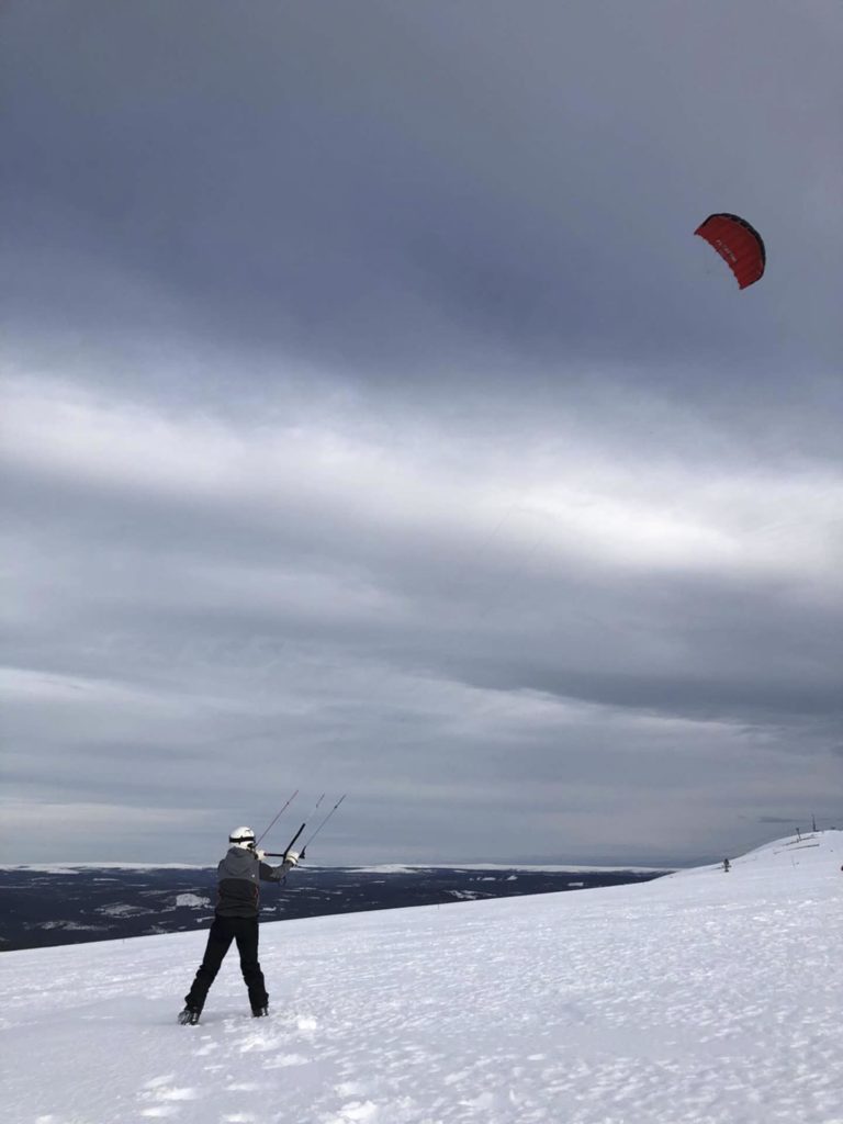 Person holder kite på snøkledd fjell