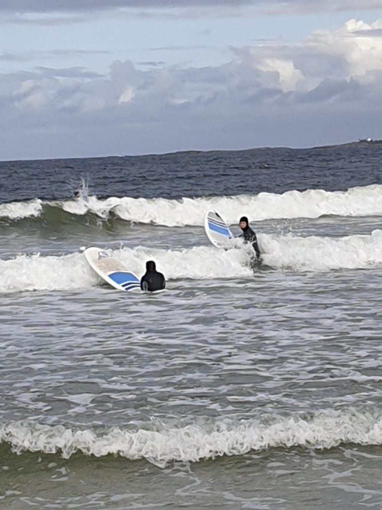To personer på surfebrett padler ut i havet