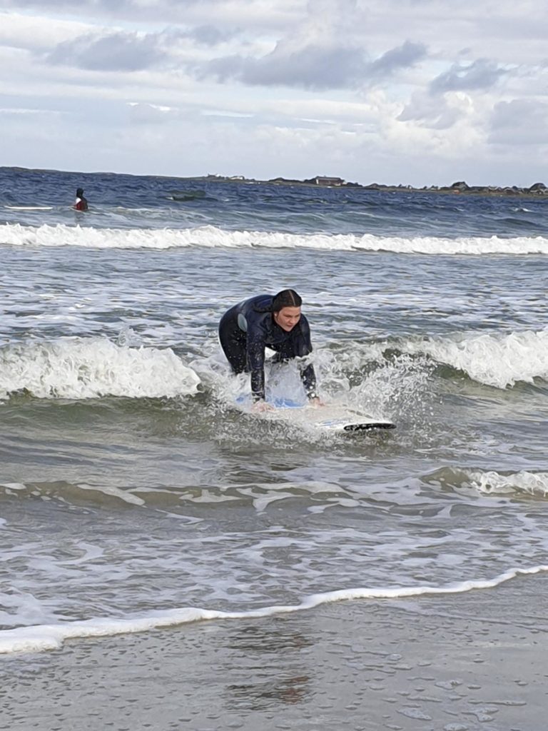 Person prøver å reise seg på surfebrett i bølge
