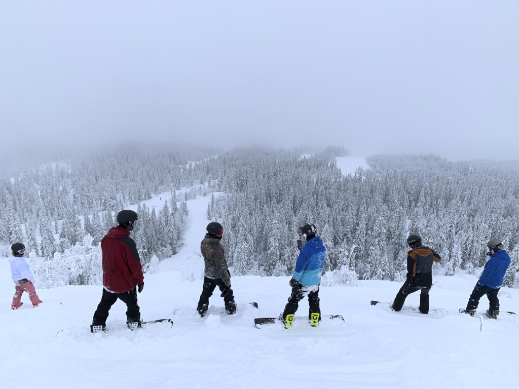 Fire unge mennekser skuer utover et skianlegg fult av puddersnø