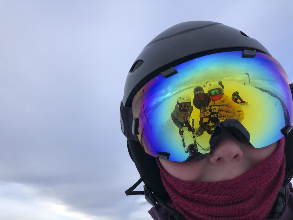 Selfie i skibriller med refleksjon av andre unge mennesker