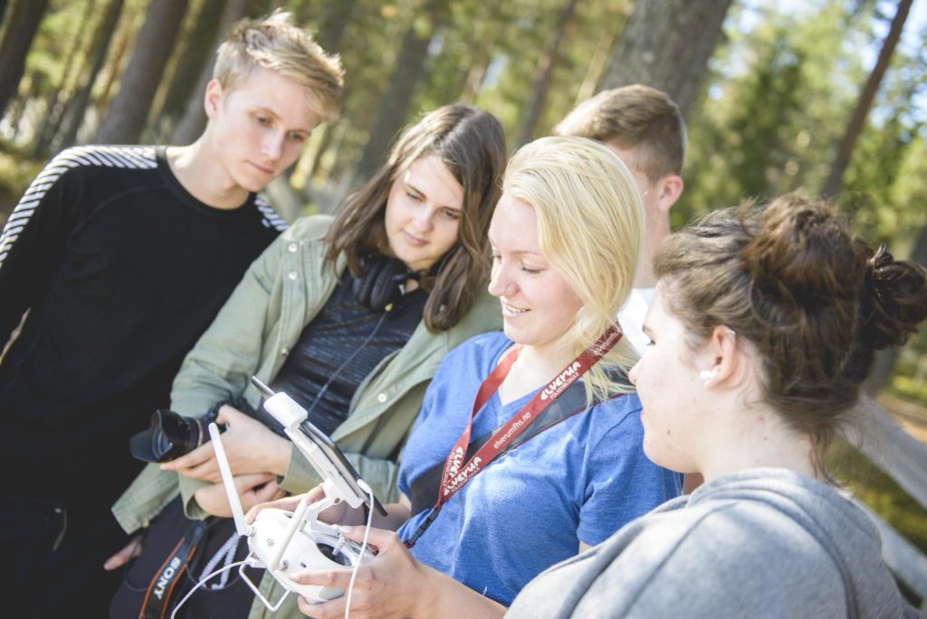 Unge mennesker ser på mens de flyr drone