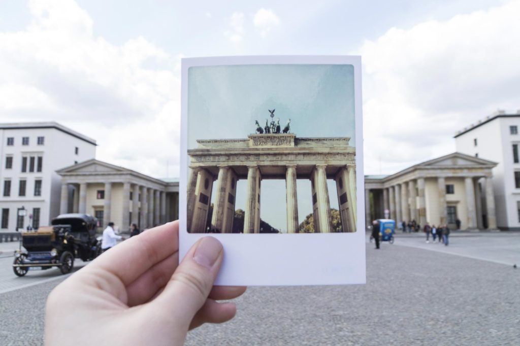 Hand holding picture of Brandenburg Gate in front of Brandenburg Gate