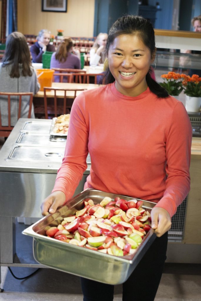 Ung kvinne smiler med masse epler