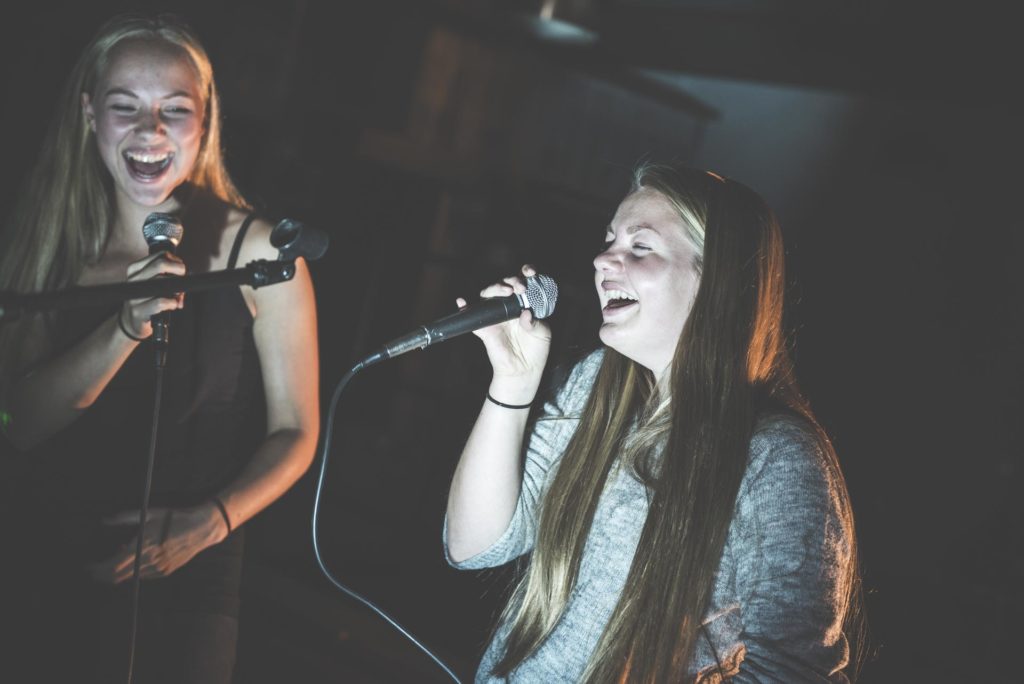 To unge kvinner synger karaoke