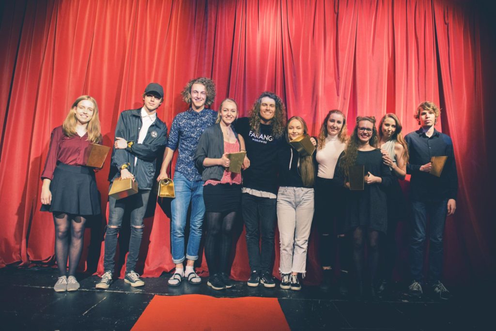 Gruppe unge mennesker poserer foran sceneteppe med filmpris