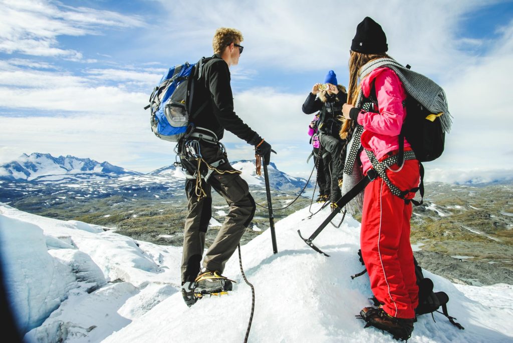 Tre unge mennesker på toppen av snøkledd fjell