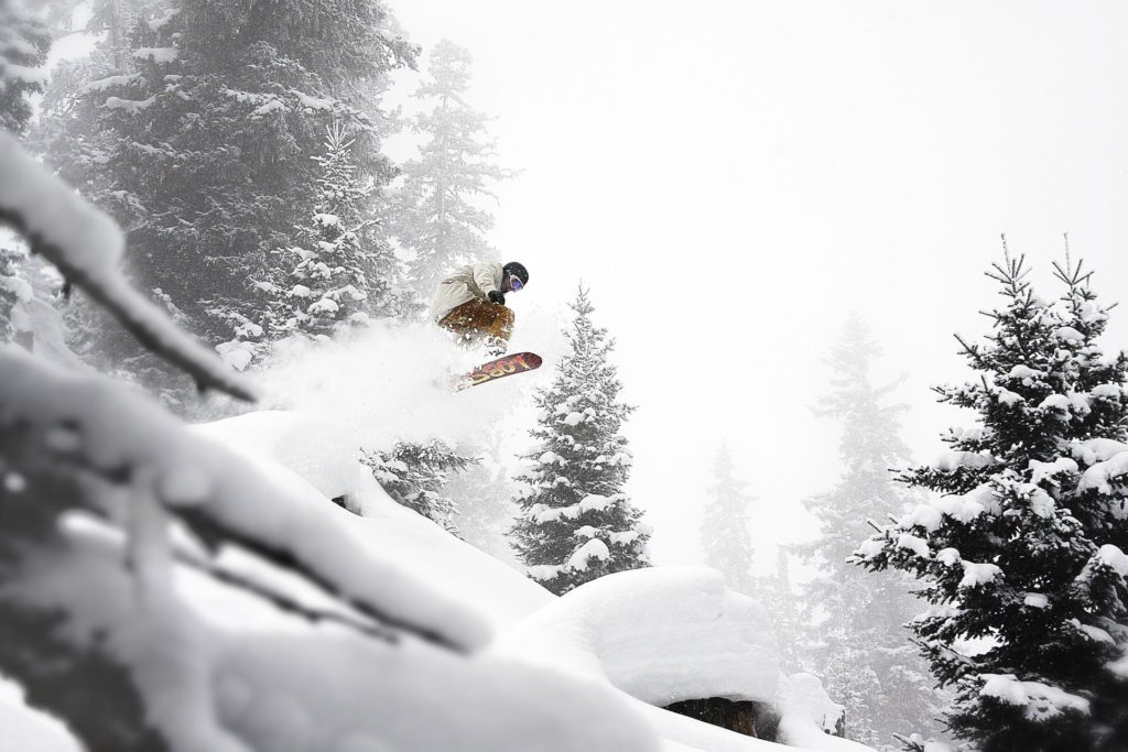 Snowboarder jumps in powder