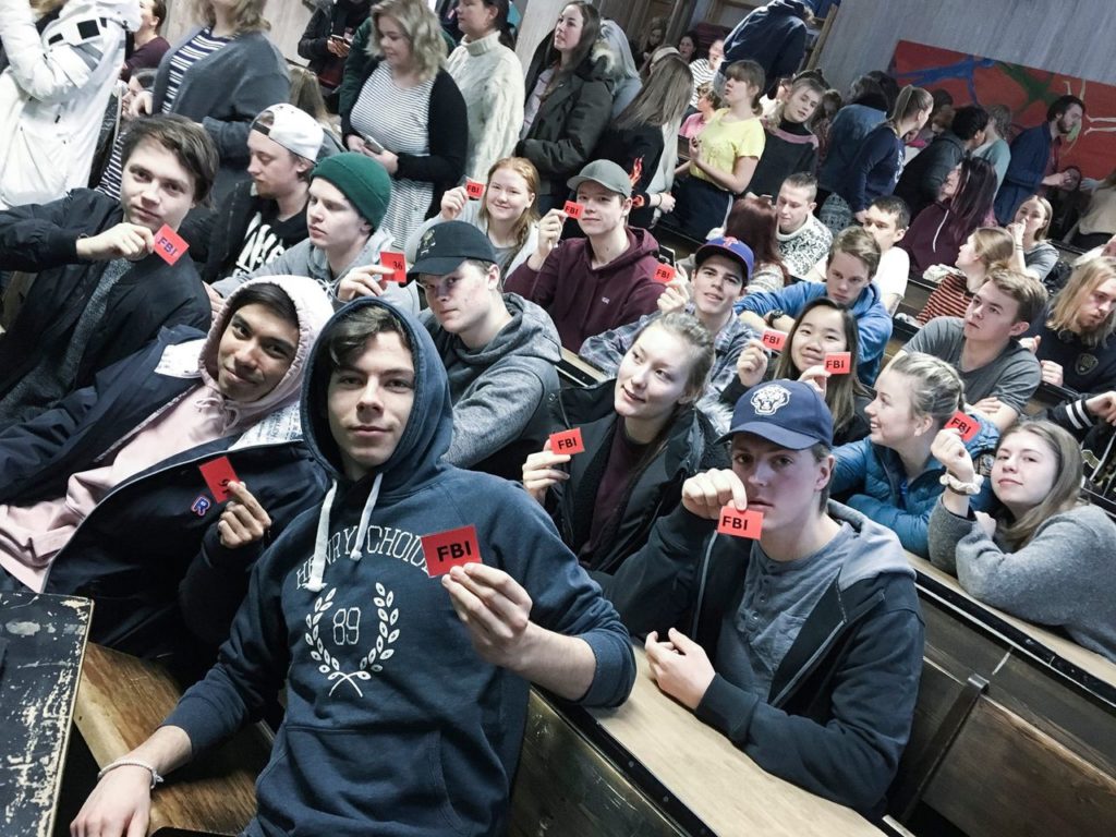 Elever i foredragssalen holder opp rødt kort