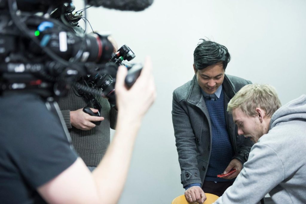 Programleder Christian Strand smiler mens elev henter mobilen sin