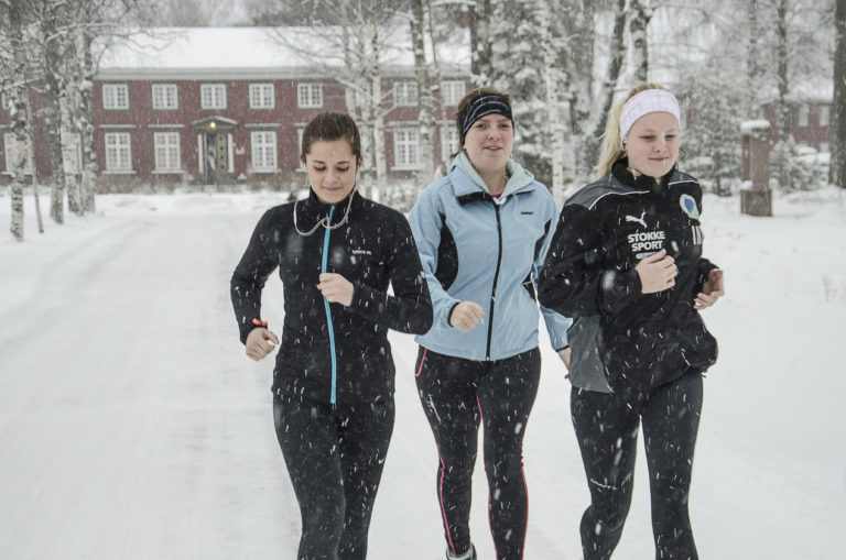 Unge kvinner jogger i snøvær