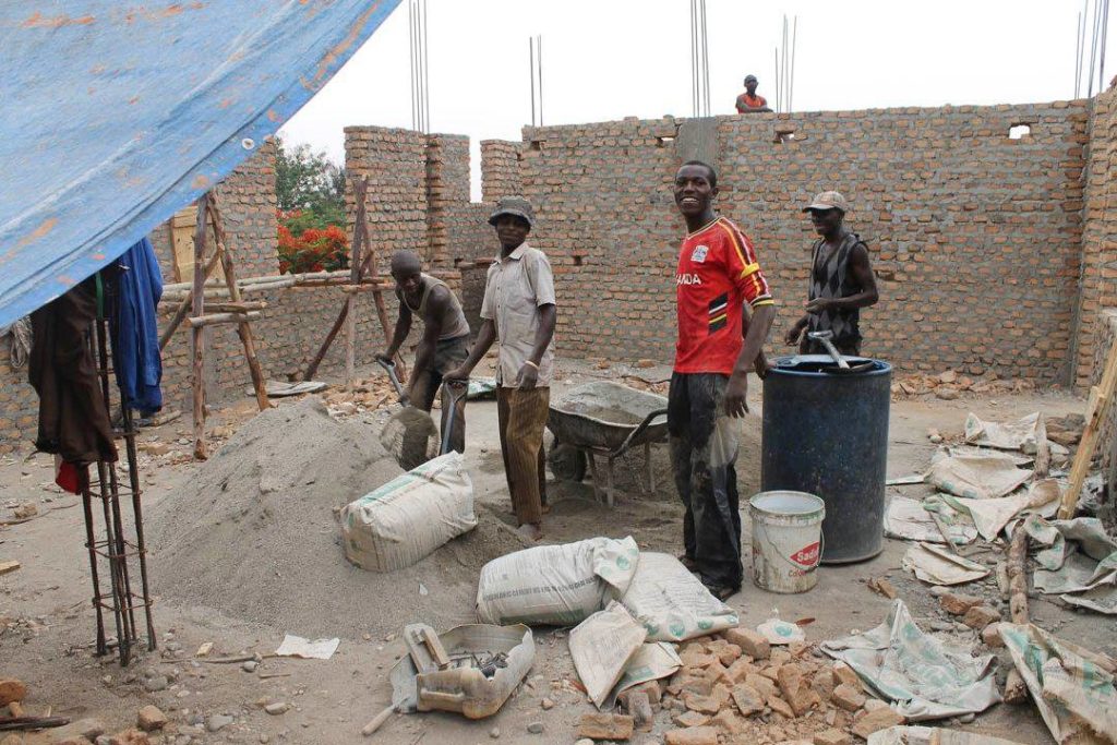 Workers build brick house in Kasese, Uganda