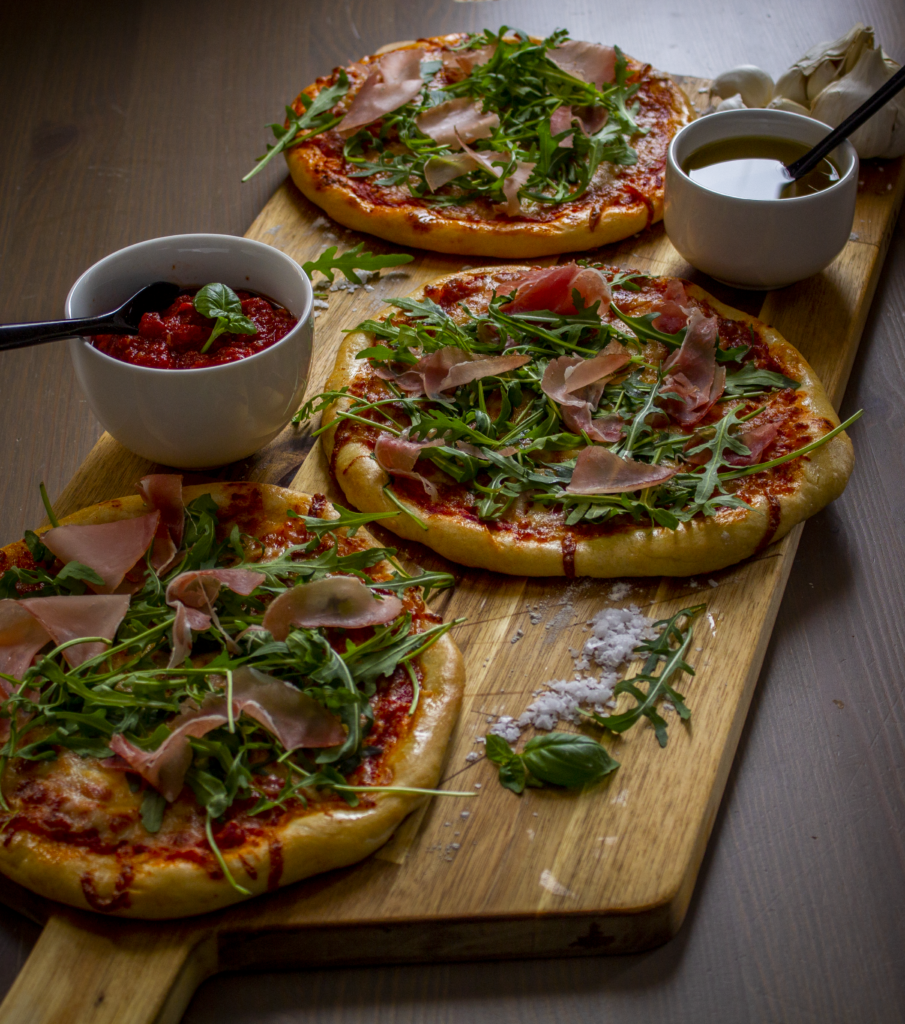 Mini pizzas on wooden boards with accessories