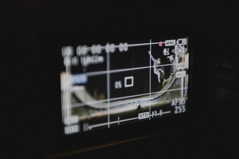 Gutt skater i skaterampe sett gjennom skjermen på et filmkamera